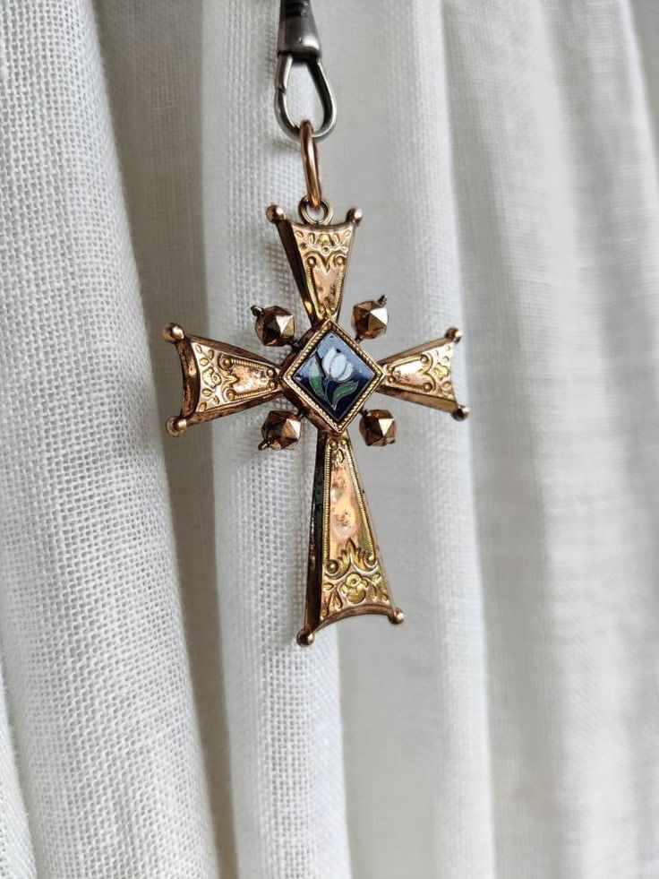 Antique cross pendant, dating from the nineteenth century, rose gold plated, engraved and enameled. There is a religious motif on one side and a floral motif on the other. The cross shows several signs of wear. There are a few chips on the enameled part with a flower. The plating is gone in places and there are small marks and indentations. The cross is very light. Dimensions: about 5.9 cm x 3.8 cm. Possible variations of color due to the light. Antique Cross Necklaces For Collectibles, Victorian Hallmarked Cross Pendant Jewelry, Antique Bronze Crucifix Jewelry, Antique Collectible Cross Jewelry, Antique Crucifix Collectible Jewelry, Victorian Engraved Enamel Necklaces, Antique Collectible Crucifix Jewelry, Antique Engraved Cross Pendant Necklace, Antique Engraved Cross Necklace