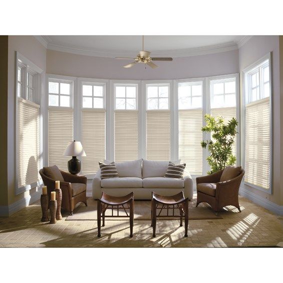 a living room filled with lots of furniture and large windows covered in white blinds on top of them