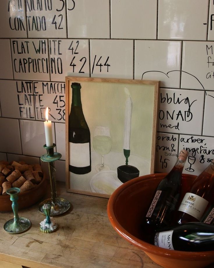 a table with bottles of wine and a candle on it next to a framed photo