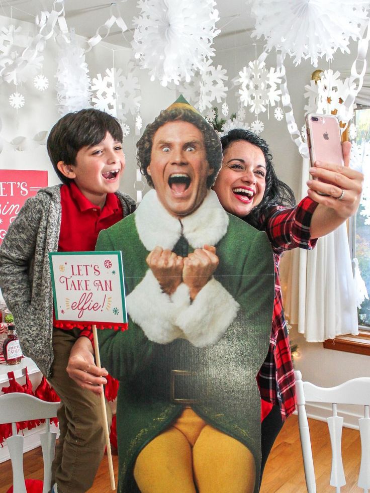 a man and woman taking a selfie in front of a christmas photo