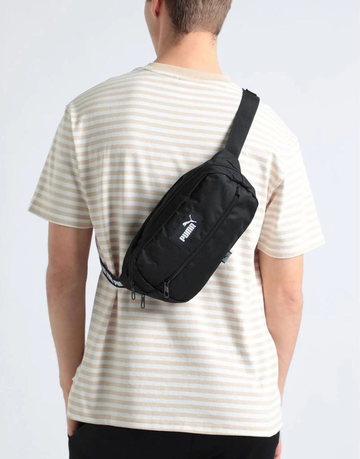 a man wearing a white and black striped t - shirt is holding a fanny bag