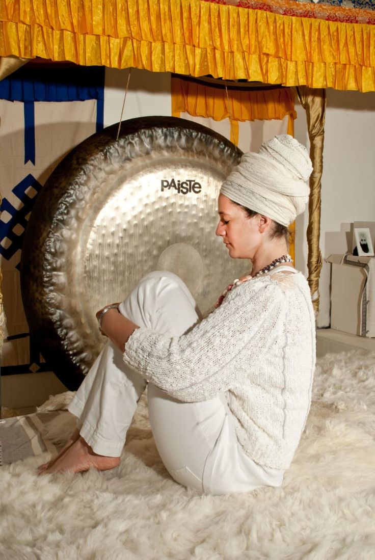 a woman sitting on top of a bed next to a gong