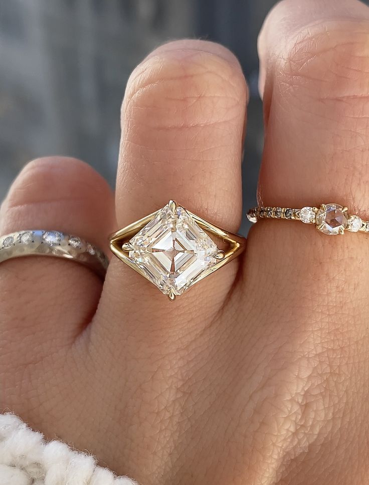 a woman's hand with two different rings on it and an engagement ring in the middle