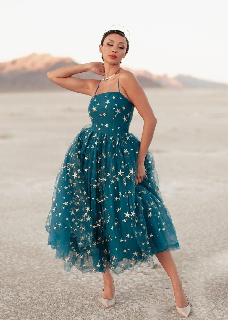 a woman in a teal dress with stars on it is posing for the camera