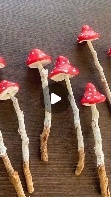 several small red mushrooms sitting on top of wooden sticks