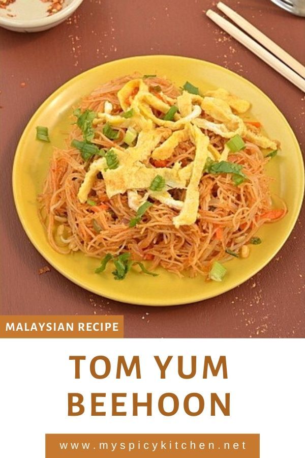 a yellow plate filled with noodles and vegetables on top of a table next to chopsticks