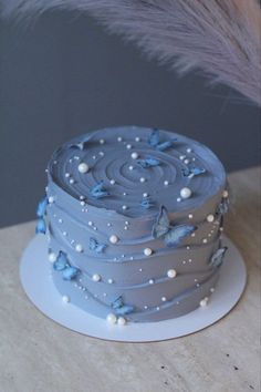 a blue cake sitting on top of a white plate next to a tall purple feather