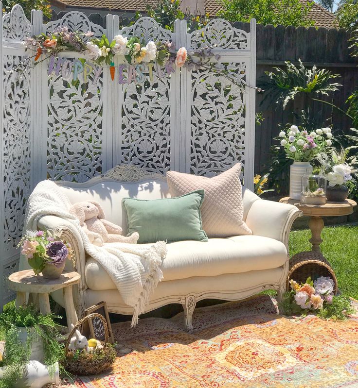 a white couch sitting on top of a lush green field next to a wooden fence