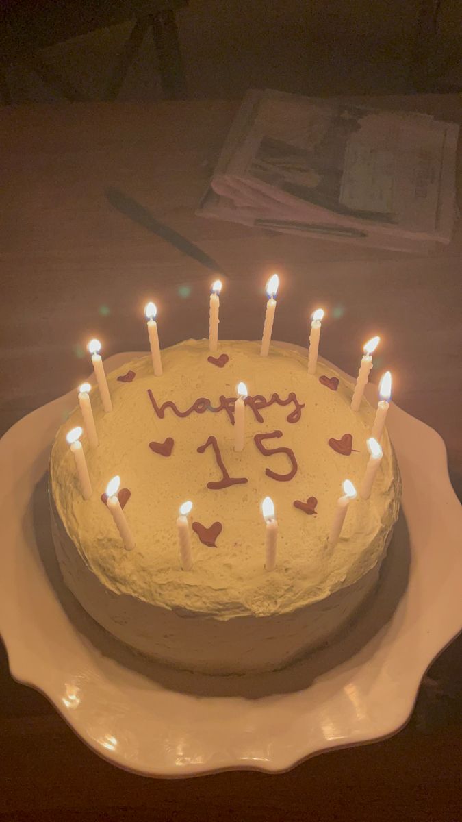 a birthday cake with white frosting and lots of lit candles in the shape of hearts