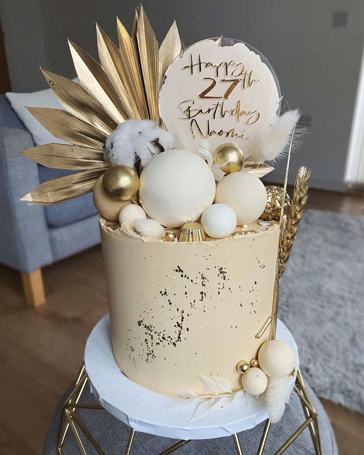 a birthday cake decorated with gold and white decorations