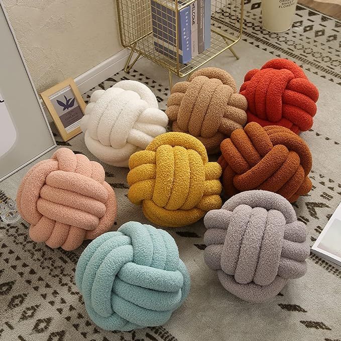 six different colored knot pillows sitting on top of a rug