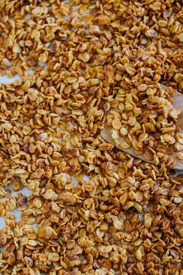 a wooden spoon filled with granola on top of a table