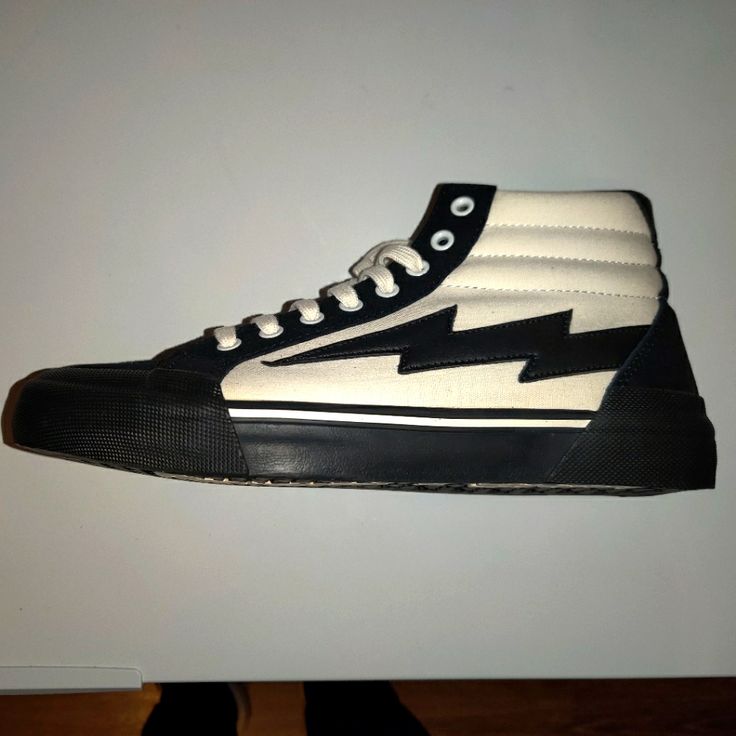 a pair of black and white high top shoes with lightning bolt on the soles