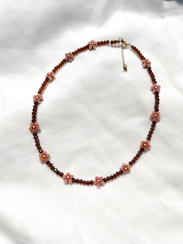 adorn yourself with the rich, chocolatey hues of the cocoa blossom necklace 🤎 ❥ bead assortment: mini brown glass crystals & acrylic flower beads  ❥ length: 16, 18 or 20 inches + extension chain with heart tag ❥ necklace findings: gold or silver plated stainless steel & tarnish resistant ⊹ ₊  ₊ ⊹⊹ ₊  ₊ ⊹⊹ ₊   ʚ♡⃛ɞ jewelry care tips ʚ♡⃛ɞ ❥ don't leave your beaded jewelry sitting in the sun ❥ avoid excessive stretching or pulling on your necklace ა heavenly made in NC ໒꒱ Brown Flower-shaped Beaded Jewelry, Accessories Minimalist, Brown Necklace, Boho Choker, Acrylic Flowers, Fall Accessories, Daisy Flower, Autumn Fall, Tag Necklace