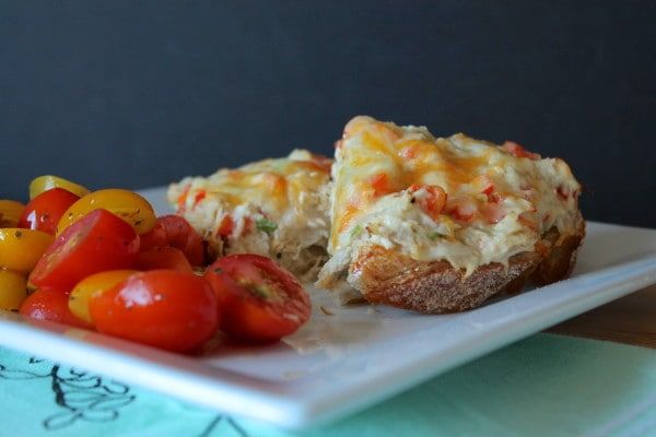 a white plate topped with bread covered in cheese and tomatoes