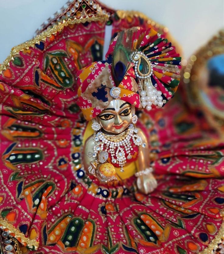 a colorfully decorated figurine sitting on top of a red cloth covered tray