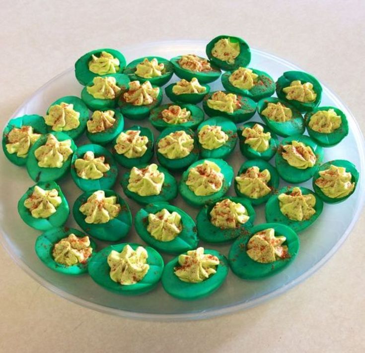 there are many green cupcakes with yellow frosting on the top and bottom