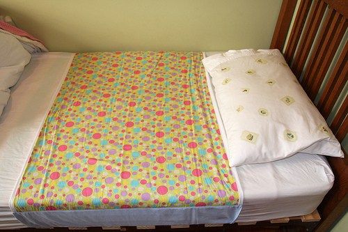 an unmade bed with white sheets and colorful flowers on the bedspread is shown