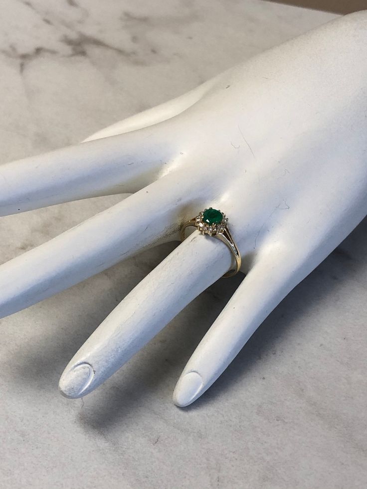 A Classic and Beautiful 14kt Yellow Gold Lady's Diamond and Emerald Ring consisting of a 5mm round genuine Emerald gemstone 3/4ct approx total weight set wtih 4 prongs in center surrounded by a halo of full cut round faceted diamonds .15ct approx total weight all prong set in finger size 6 3/4. May is the Birthstone for Emerald. This item would Retail for $2,550.00 Heirloom Diamond Ring With Birthstone In Round Cut, Classic Solitaire Diamond Ring For May Birthstone, Classic Brilliant Cut May Birthstone Ring, Emerald Ring With Brilliant Cut For Promise, Classic Diamond Ring With Vvs Clarity For May Birthstone, Fine Jewelry Round Emerald Diamond Ring, Emerald Solitaire Diamond Ring For Anniversary, Classic Diamond Ring With May Birthstone, Emerald Ring With Vvs Clarity Round Cut