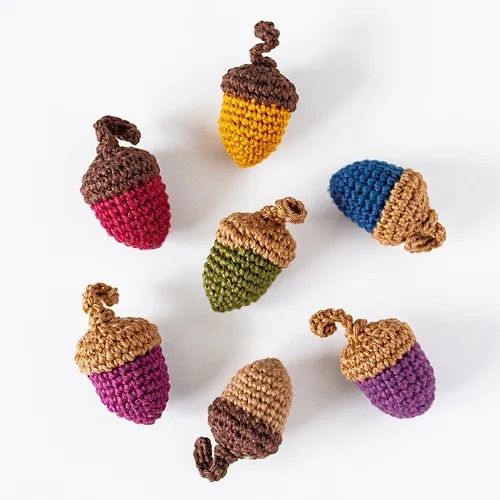 six crocheted acorns are shown in different colors