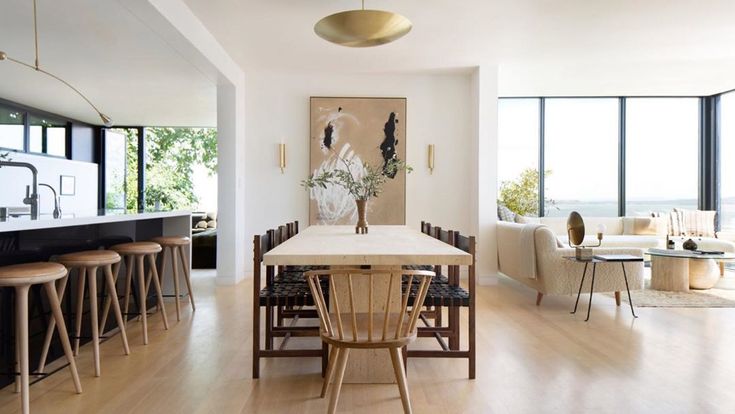 a dining room table and chairs in front of large windows