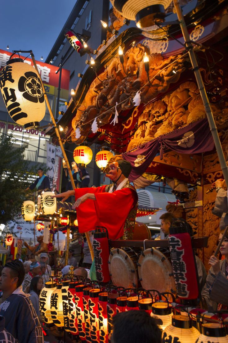 a man dressed in traditional chinese garb and holding a flag at an outdoor market