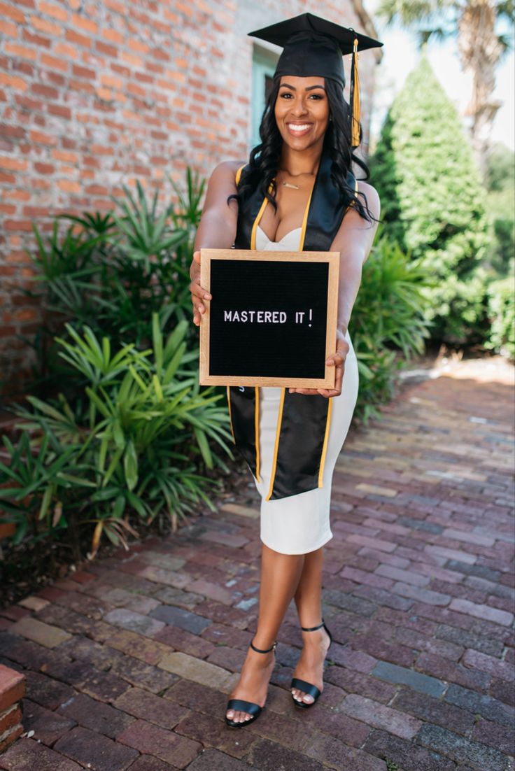 a woman wearing a graduation cap and gown holding a sign that says master d i