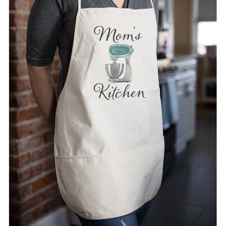 a woman wearing an apron with the words mom's kitchen on it and a mixer behind her