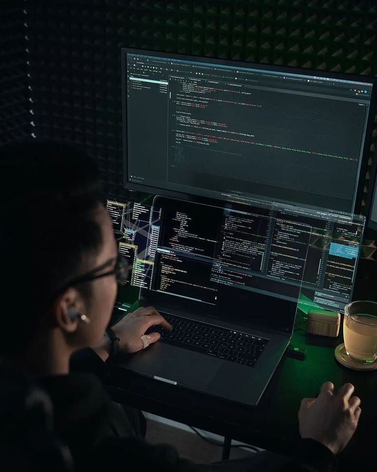 a person sitting at a desk with a laptop and mouse in front of them, looking at the screen