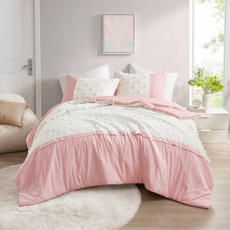 a bed with pink and white comforters in a room