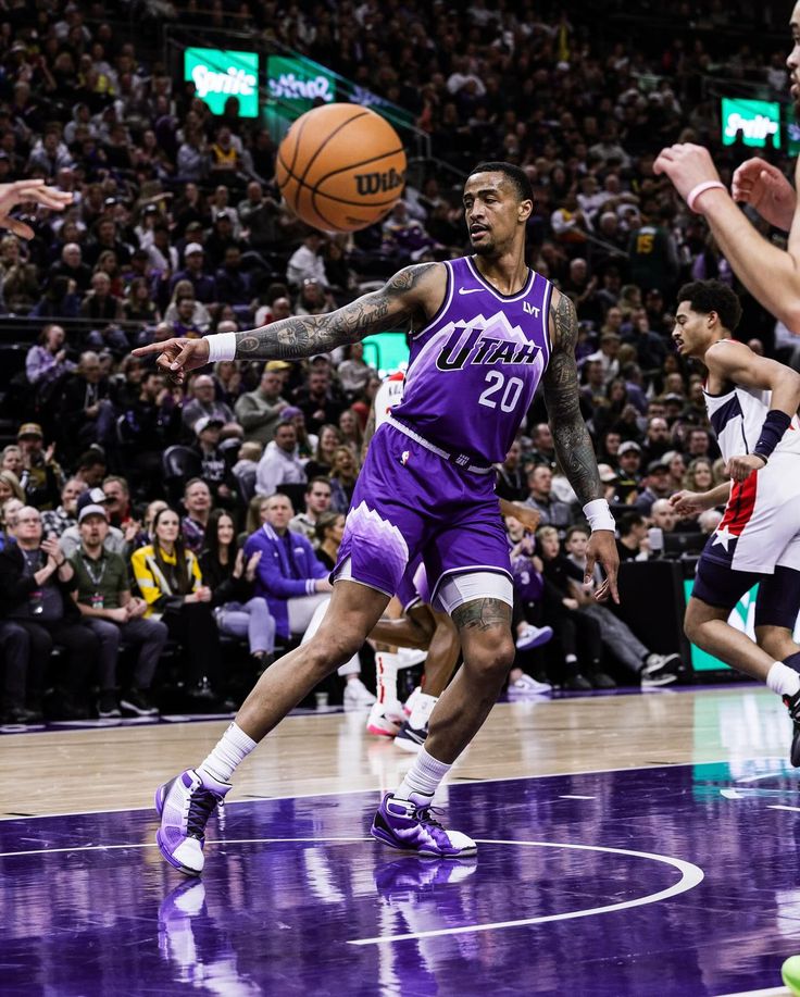 a basketball player in purple is about to pass the ball while other players look on