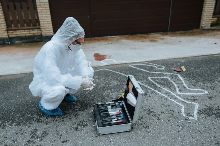 a person in a white suit and protective clothing crouching down next to an open toolbox