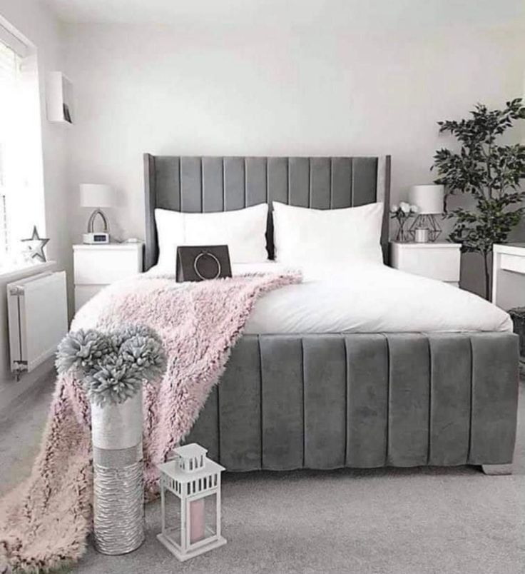 a bedroom with white walls and grey bedding, pink rugs on the floor