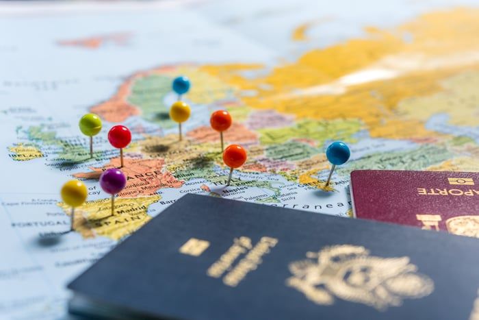 a passport and pins on top of a map with the countries marked in red, yellow, blue, and green