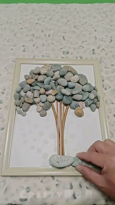 a person is painting rocks in a frame on a table with green and white wallpaper