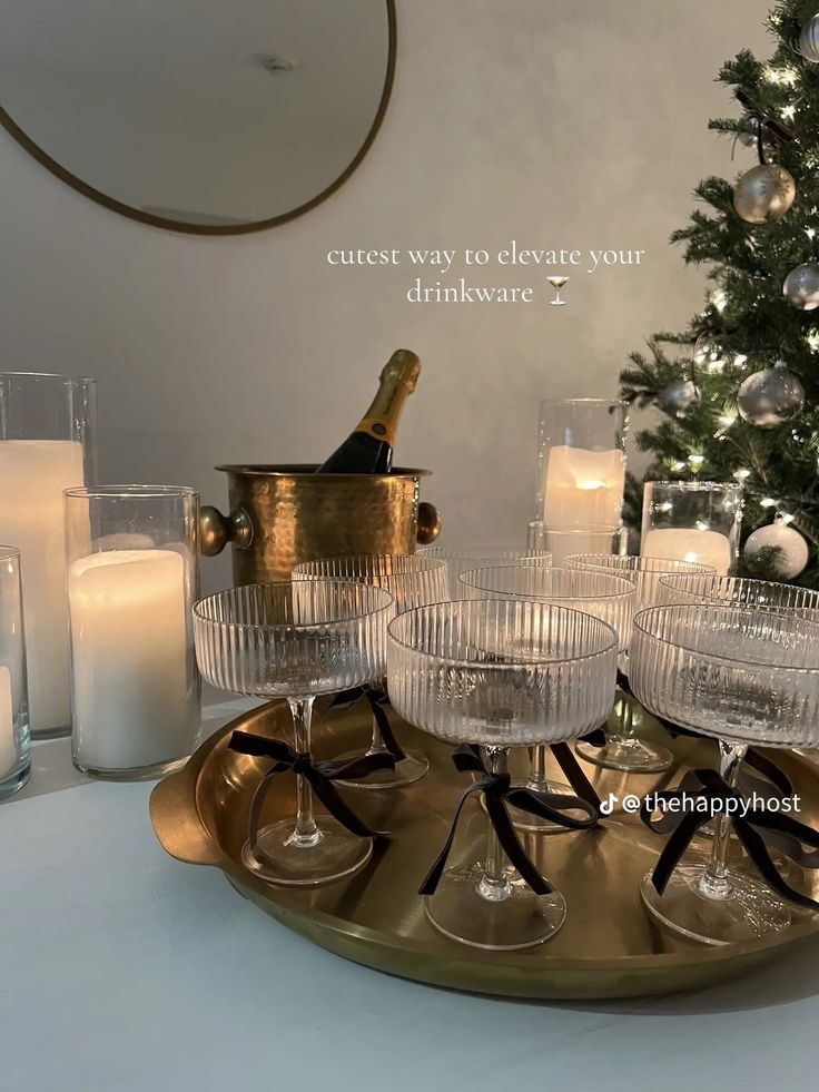 champagne glasses and candles on a tray with a christmas tree in the background that says, cute way to elevate your drinkware