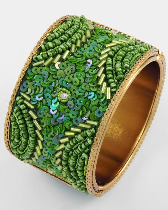 Green Sequin and Beaded Cuff Bracelets This bracelet is a cuff style with a spring closure. Green sequins, bugle beads and seed beads are combined in a beautiful design. The gold tone metal is braided along the edges of the bracelet. The inside is smooth god tone metal. The spring closure makes them secure, easy to put on and remove.  This pretty bracelet is great for that festival or Boho look. A boutique item accessory. diameter is 2 1/4". the width is 1 3/4" Green Bangle Cuff Bracelet For Party, Handmade Green Bangle For Party, Green Beaded Metal Bangle Bracelets, Beaded Cuff Bracelet For Party, Adjustable Green Cuff Bracelet For Party, Adjustable Green Cuff Bracelet For Parties, Party Beaded Cuff Bracelet, Gold Beaded Bangle Bracelet For Party, Green Cuff Bracelet For Party