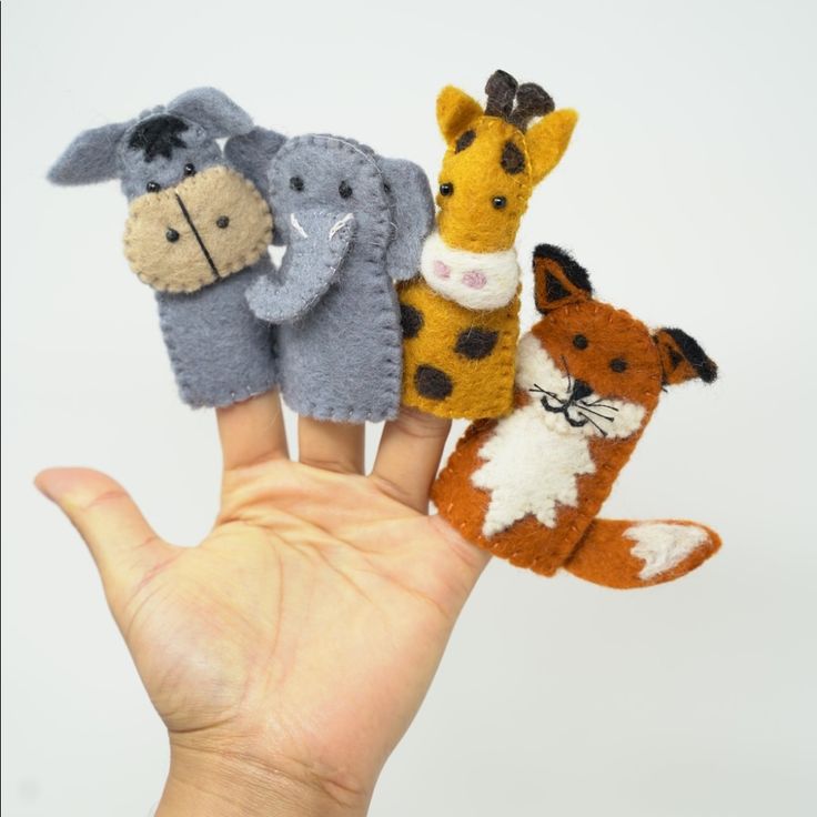 four finger puppets in the shape of animals are held by a person's hand