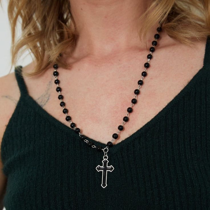 Indulge in edgy elegance with our Silver Gothic Beaded Cross Charm Necklace. Made with stunning black beads and a beautifully intricate cross charm, this necklace is the perfect accessory for anyone looking to make a statement. Showcase your unique style and add a touch of sophistication to any outfit with this one-of-a-kind piece! Good to Know: Adjustable fastening  Silver Plated  Nickel Free  Charm Size 20mm x 10mm  Necklace Length 21" - 24" with Adjuster Gothic Beaded Cross Jewelry, Black Cross Jewelry With 8mm Beads, Edgy Black Beaded Jewelry, Spiritual Black Cross Beaded Necklace, Black Beaded Cross-shaped Rosary, Black Beaded Cross Rosary, Black Spiritual Cross Pendant Necklace, Elegant Black Crucifix Cross Necklace, Edgy Black Cross Necklace