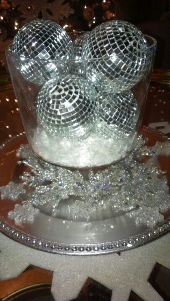 some disco balls are in a glass bowl on a platter with snow flakes