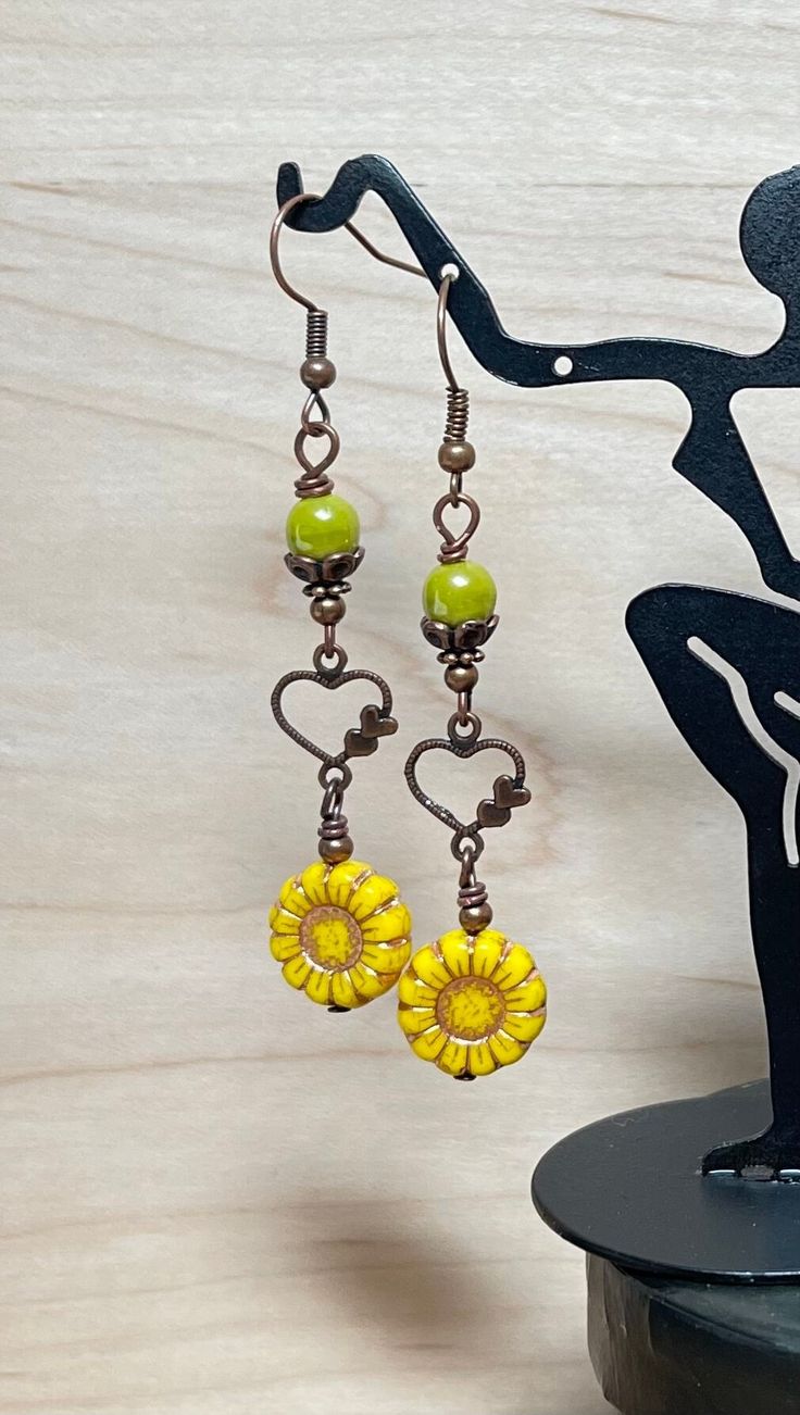 Pretty springtime boho dangle earrings.  These earrings are created using green yellow Czech sunflower beads with a copper wash, avocado green Czech beads, and antique copper heart connectors.  These earrings are great for everyday, and make a lovely gift! Total length of earrings, including the ear wire, is 2-1/2". Thank you for visiting The Lucie Collection! Handmade Yellow Earrings For Spring, Green Heart-shaped Bohemian Earrings, Bohemian Yellow Drop Earrings, Green Bohemian Jewelry For Spring, Whimsical Green Heart-shaped Jewelry, Bohemian Wire Wrapped Flower Earrings, Yellow Bohemian Dangle Earrings, Yellow Bohemian Nickel-free Flower Earrings, Handmade Bohemian Dangle Heart Earrings