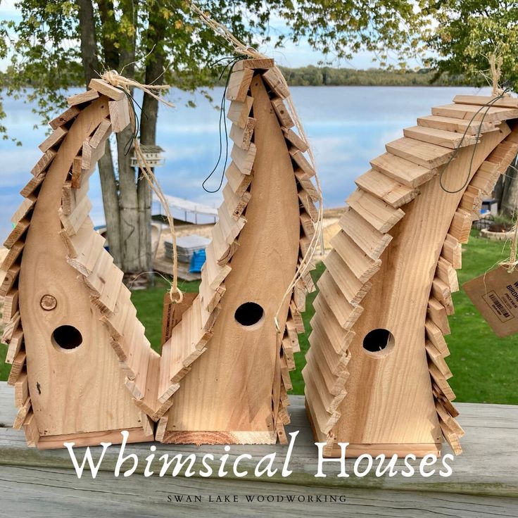 three wooden birdhouses are sitting on a porch next to the water and some trees