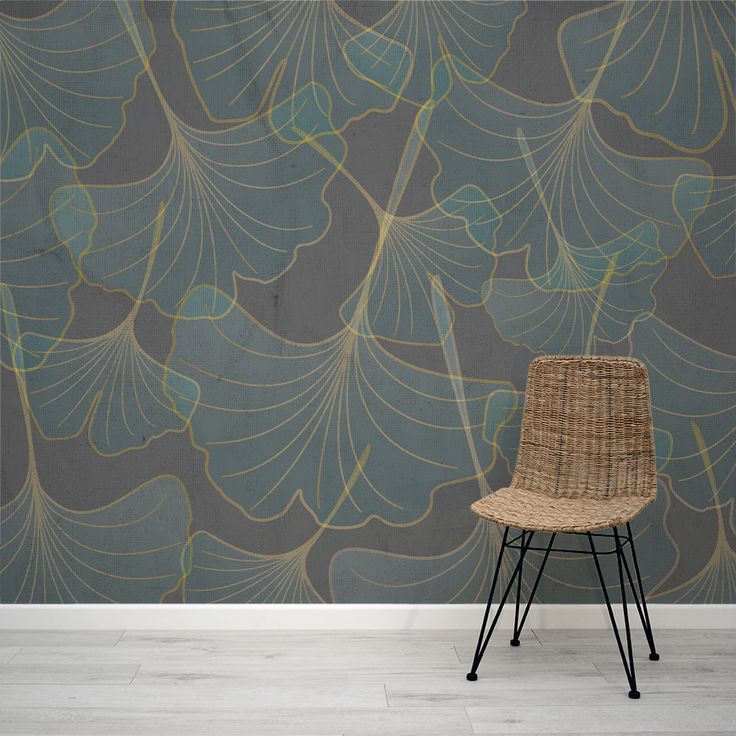 a wicker chair sitting in front of a wallpapered with large leaf designs