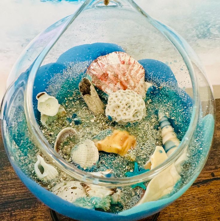 a glass bowl filled with sea shells on top of a wooden table