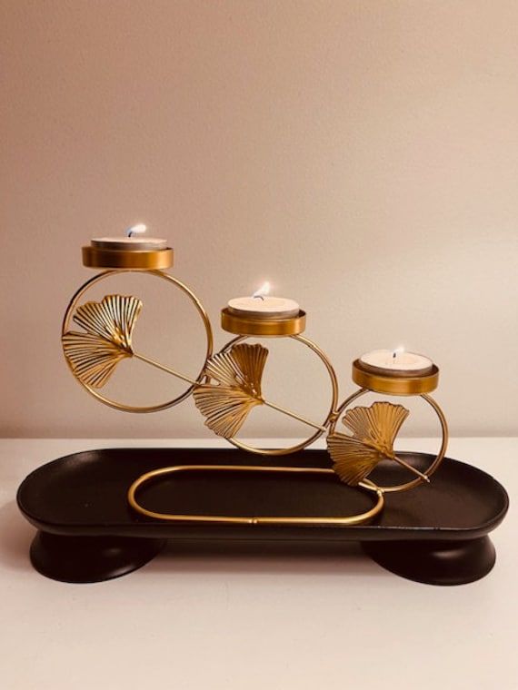 a gold and black candle holder with three candles on it's side, in the shape of a bicycle