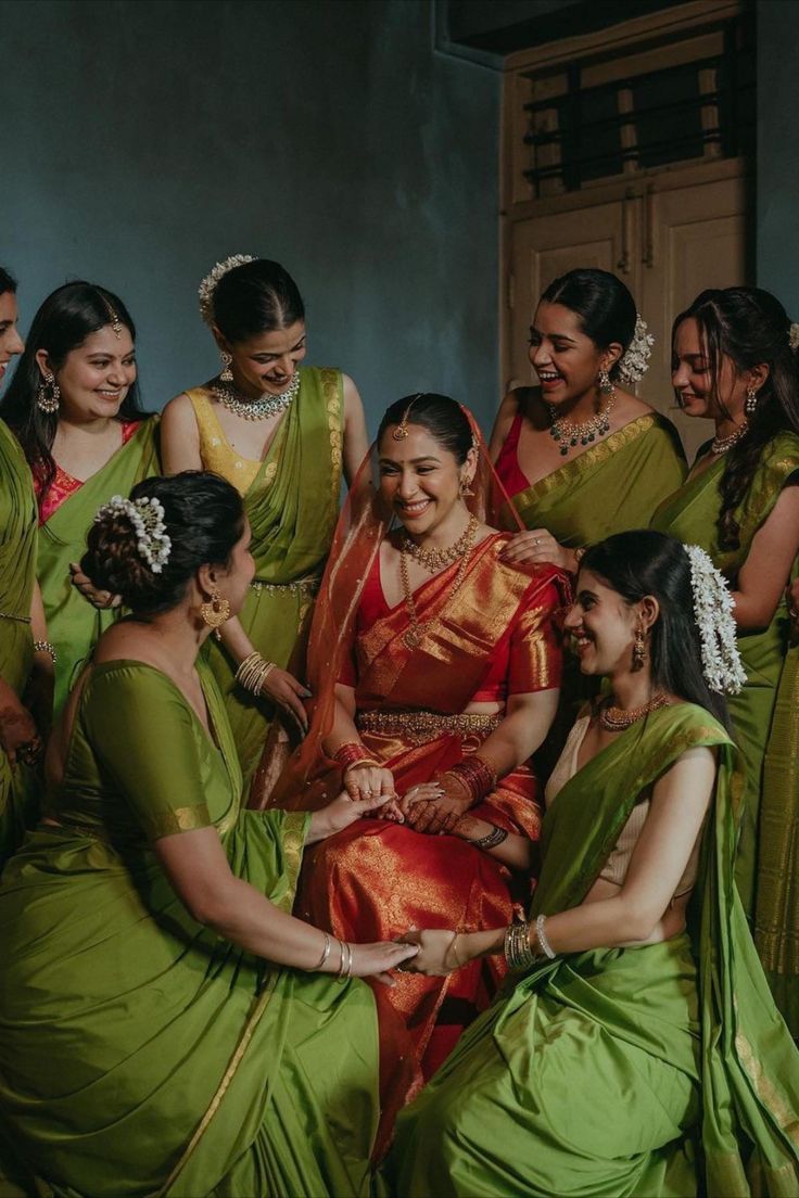 a group of women in green sari sitting next to each other