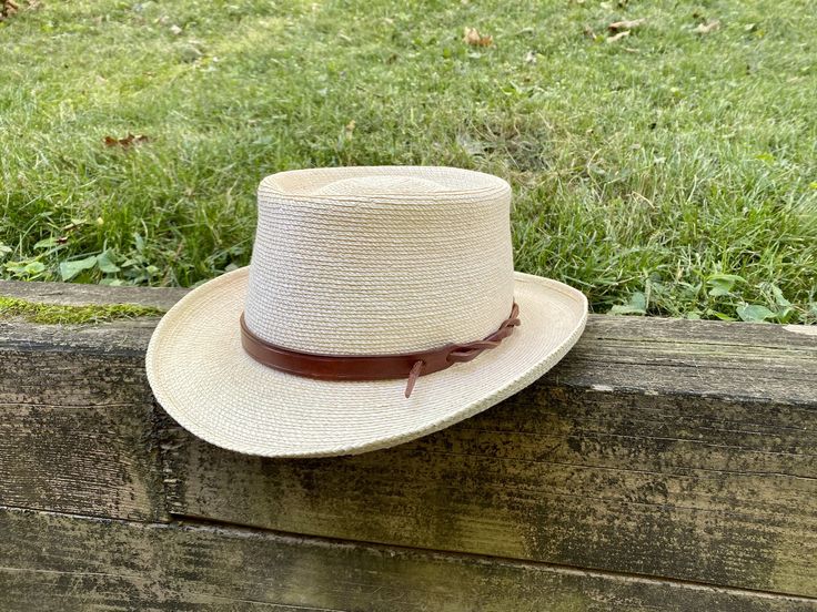 "Upgrade your favorite hat with a custom and customizable leather hat band. Perfectly adjustable to fit any size hat and can be secured in multiple ways to customize your style. Each hat band is handmade from substantial and durable full-grain vegetable tanned leather. Made to your order, the leather is cut, dyed, and finished. The edges are then beveled, burnished, and sealed for a smooth feel. Bands are 5/8\" wide. Sizes are based on the length of the wide part of the leather and can fit a ran Classic Natural Hat Bands For Outdoor, Adjustable Leather Panama Hat With Short Brim, Natural Hat Bands For Kentucky Derby, Adjustable Country Style Top Hat For Outdoor, Adjustable Leather Hat Bands With Flat Brim, Adjustable Brimmed Leather Panama Hat, Adjustable Classic Straw Hat For Ranch, Adjustable Brown Boater Hat With Flat Crown, Rustic Hat Band For Curved Brim In Natural Color