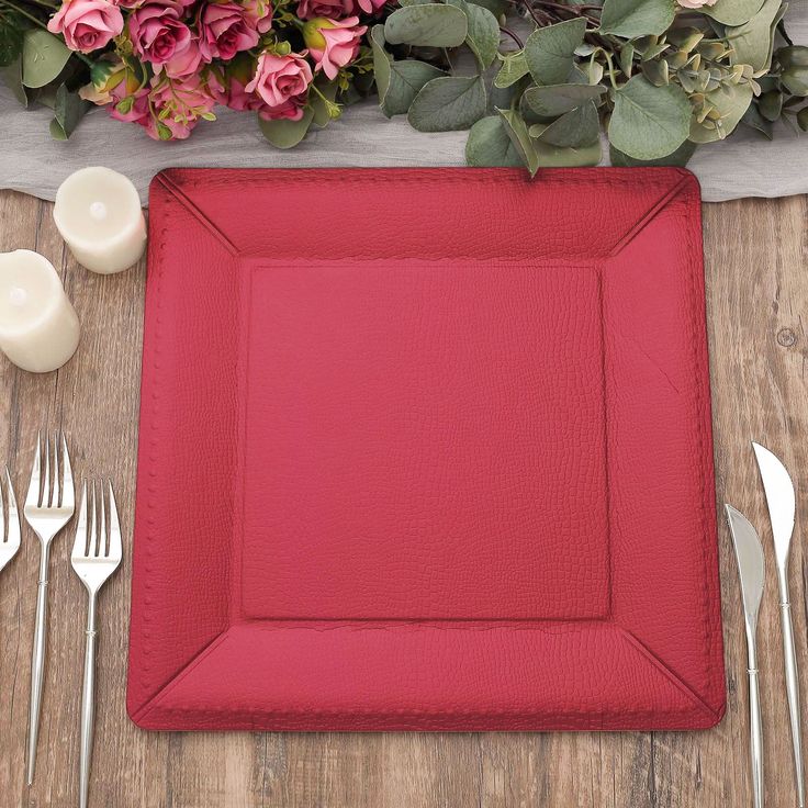 a red place setting with silverware and flowers