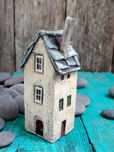 a small house made out of clay sitting on top of some black and white rocks