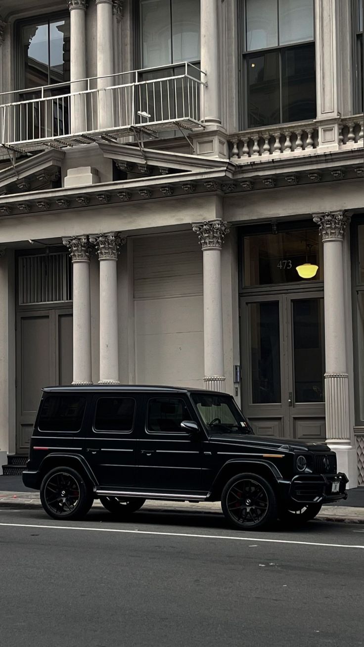 a black jeep is parked in front of a building with columns and balconies